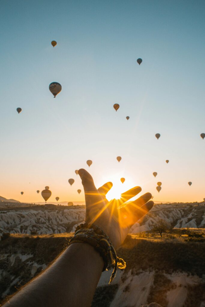 pexels-photo-2893685-2893685 Experience the magic of hot air balloons at sunrise with an outstretched hand in Cappadocia's breathtaking landscape.